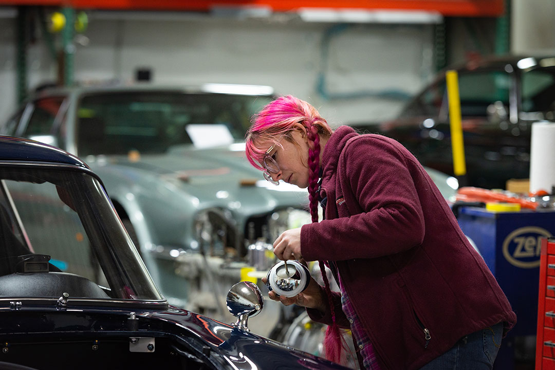 Kira Mundhenk auto restoration apprentice at Steel Wings working on an Aston Martin.