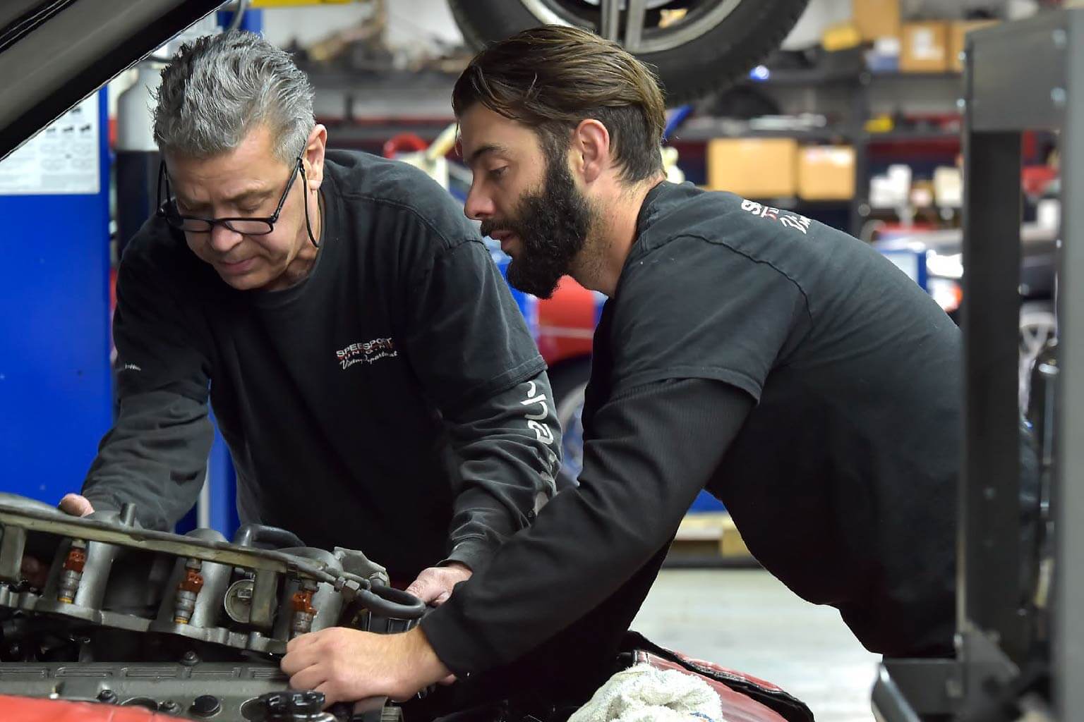 Two men working under the hood of a car