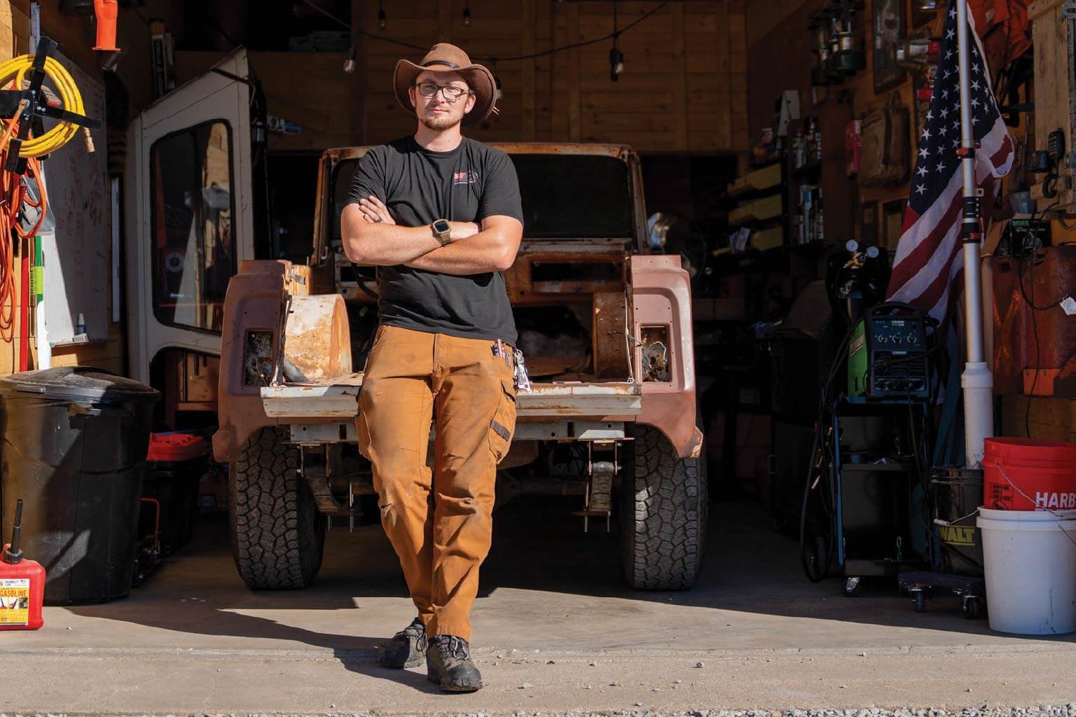Man in a hat folding his arms and leaning agains the bed of a truck